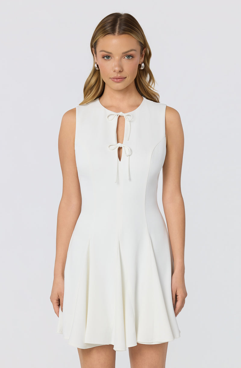 White sleeveless dress with bow ties at the neckline and pleated skirt.