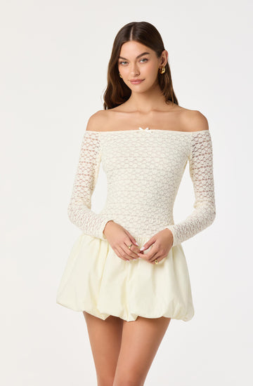 Girl in an off-shoulder cream top with lace sleeves and a cream puffy skirt.