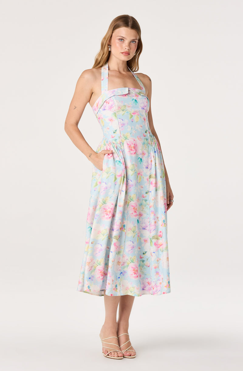 Woman in a pastel floral halter dress with pockets, midi length, and strappy heels.