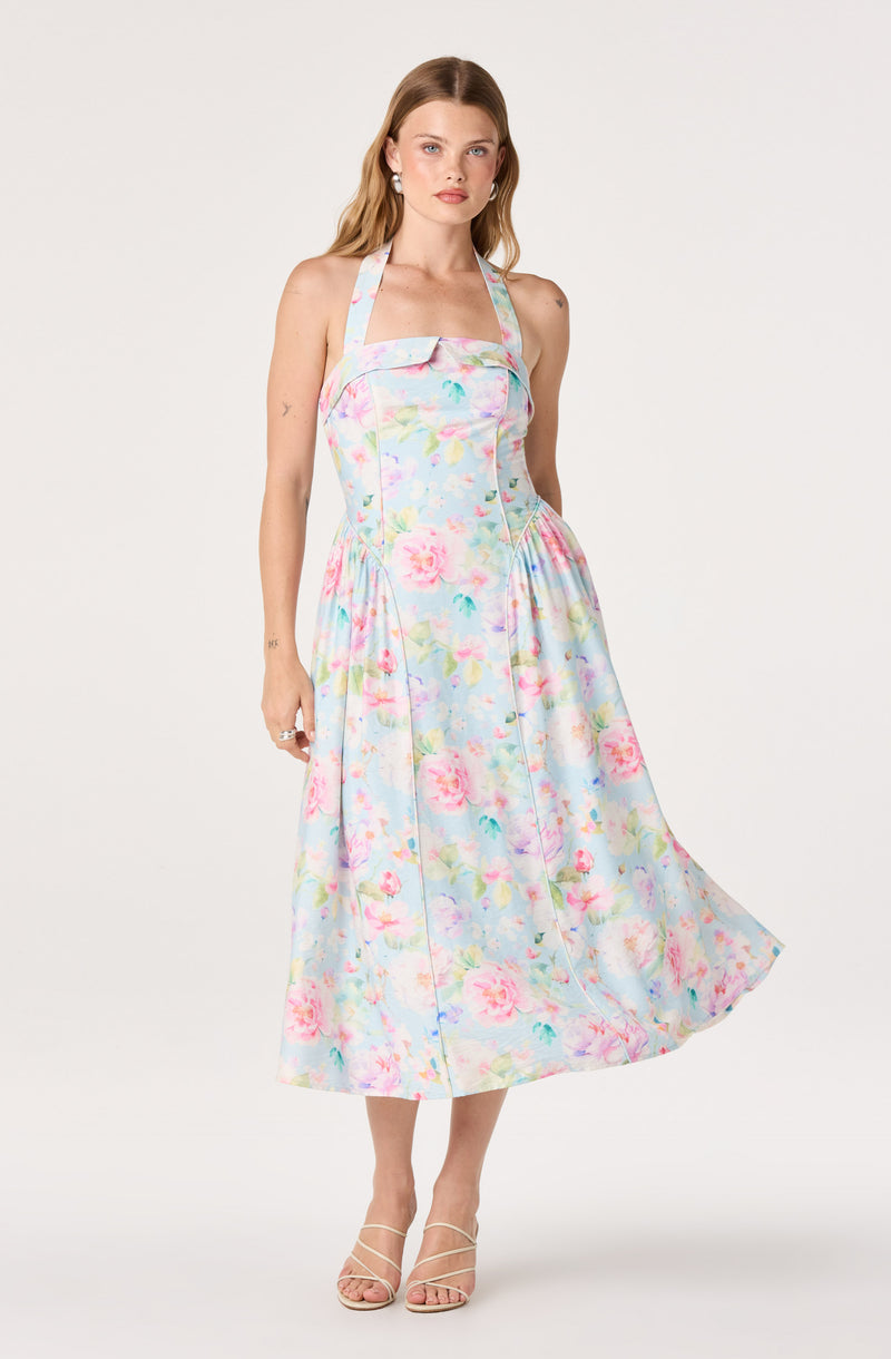 Woman in a pastel floral halter dress with a full midi skirt and strappy heels.