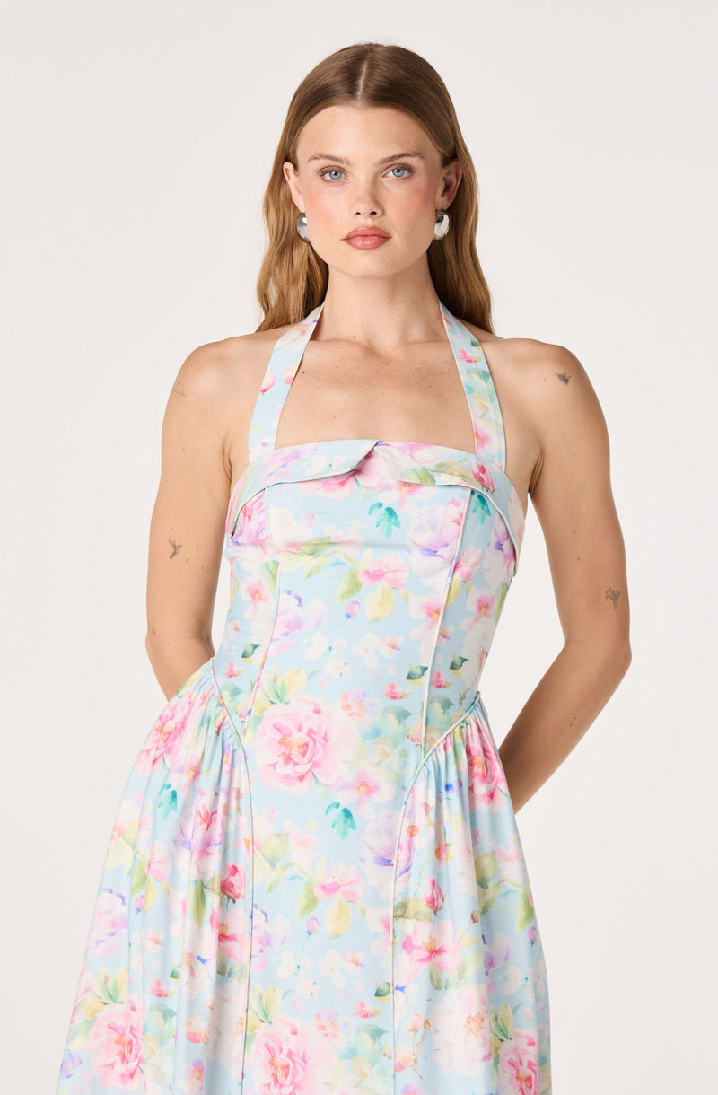 Woman in light pastel floral dress with halter neckline and fitted bodice.