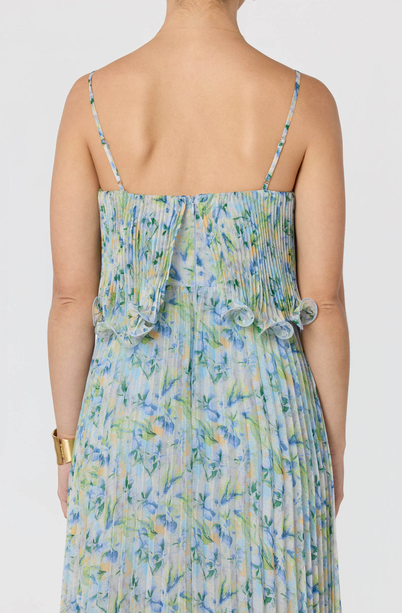 Woman in a floral, pleated, and ruffled sundress with thin spaghetti straps.