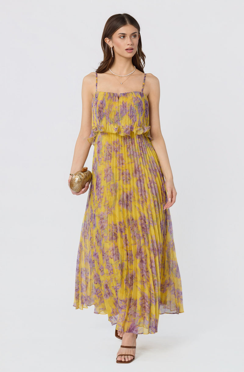 Woman wearing a yellow and purple floral printed sleeveless maxi dress with spaghetti straps.