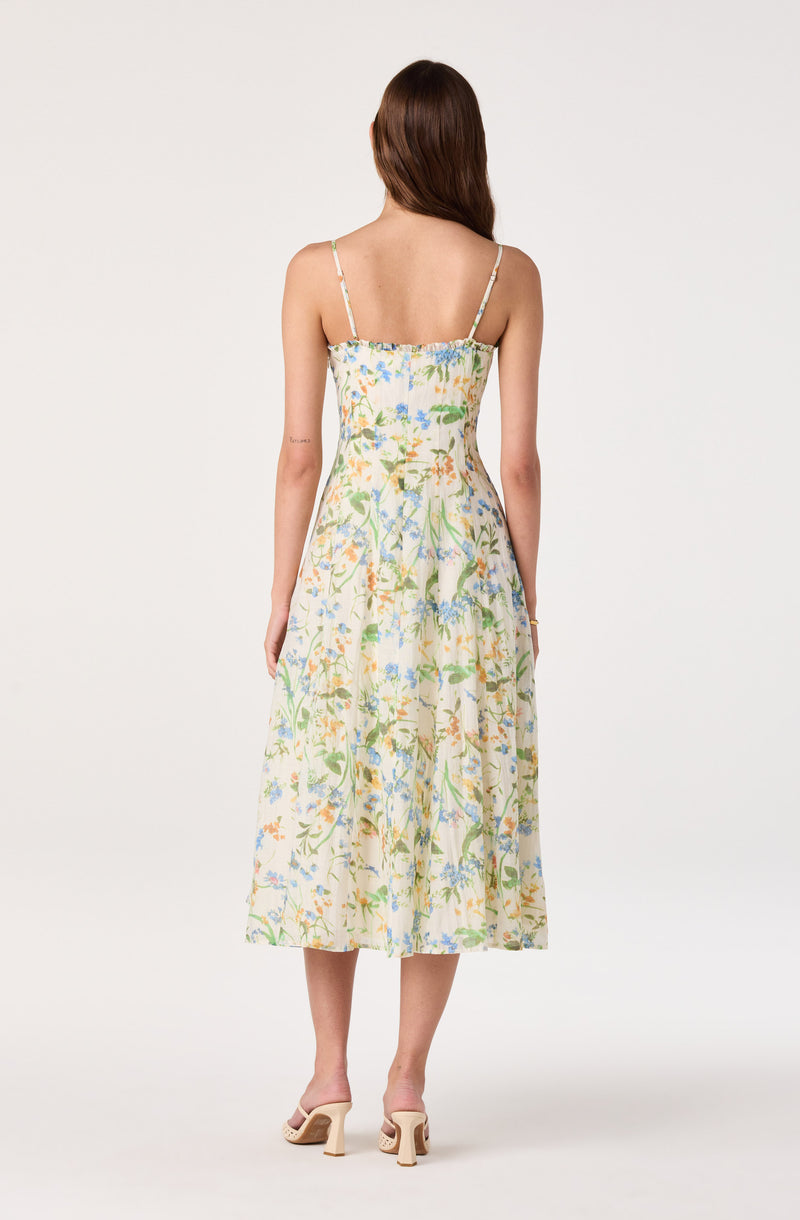 Woman wearing a cream-colored, floral print, sleeveless midi dress with thin straps.