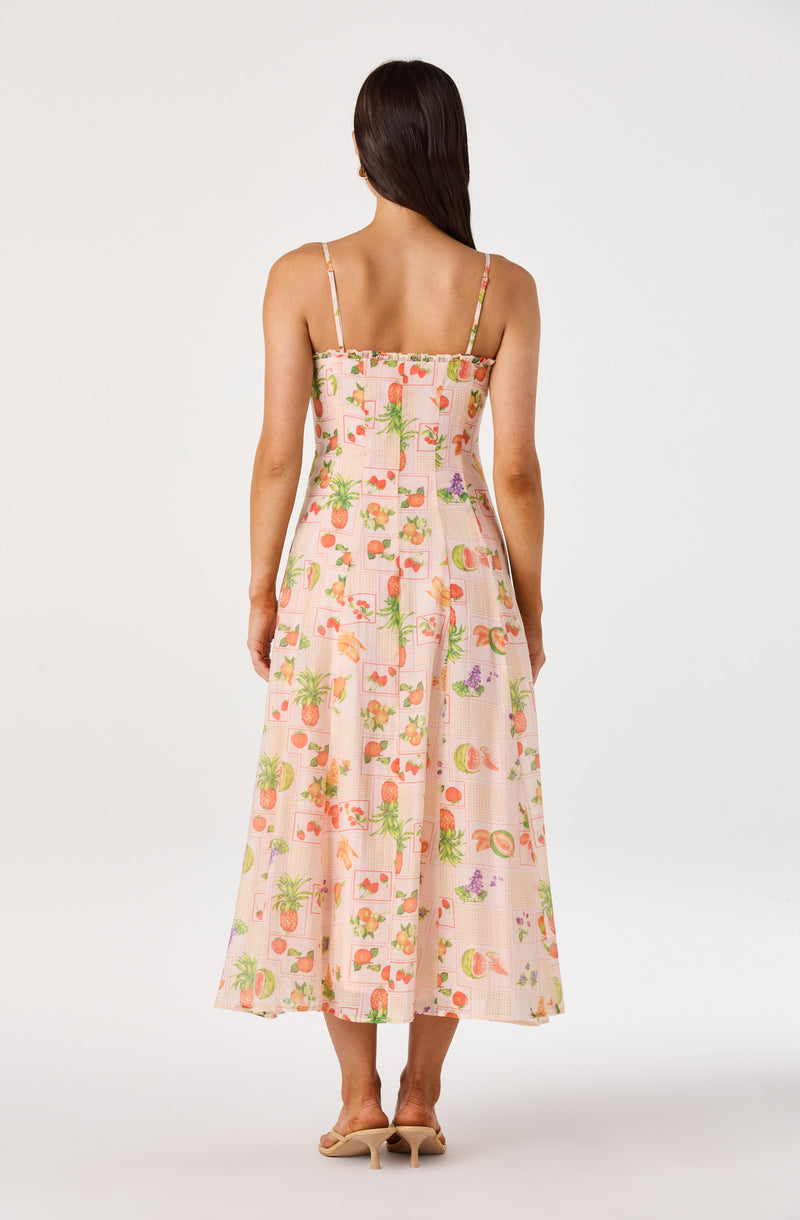 Light pink dress with colorful fruit and palm tree print, spaghetti straps, and a flowy hem.