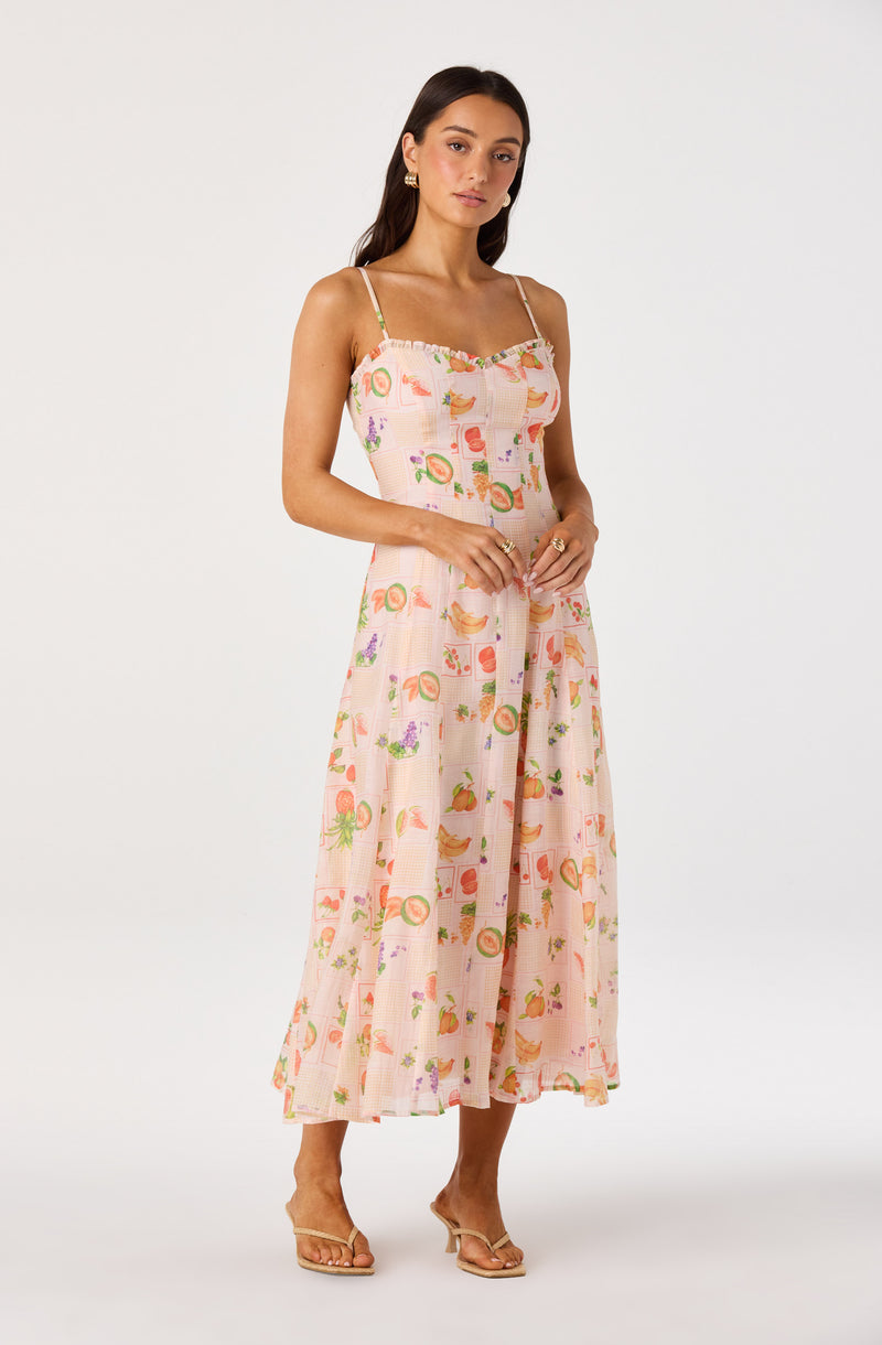 Woman wearing a pink, sleeveless, printed maxi dress with thin spaghetti straps.
