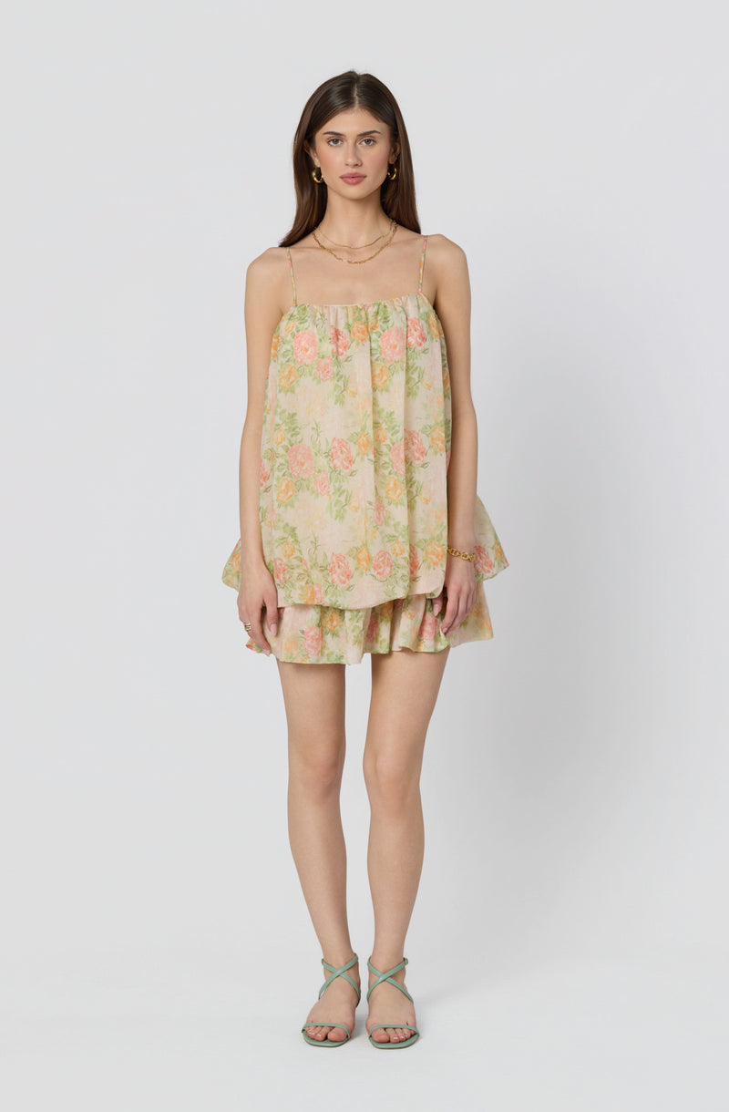 Woman in a floral pastel-colored tank top and matching shorts, strappy heels.