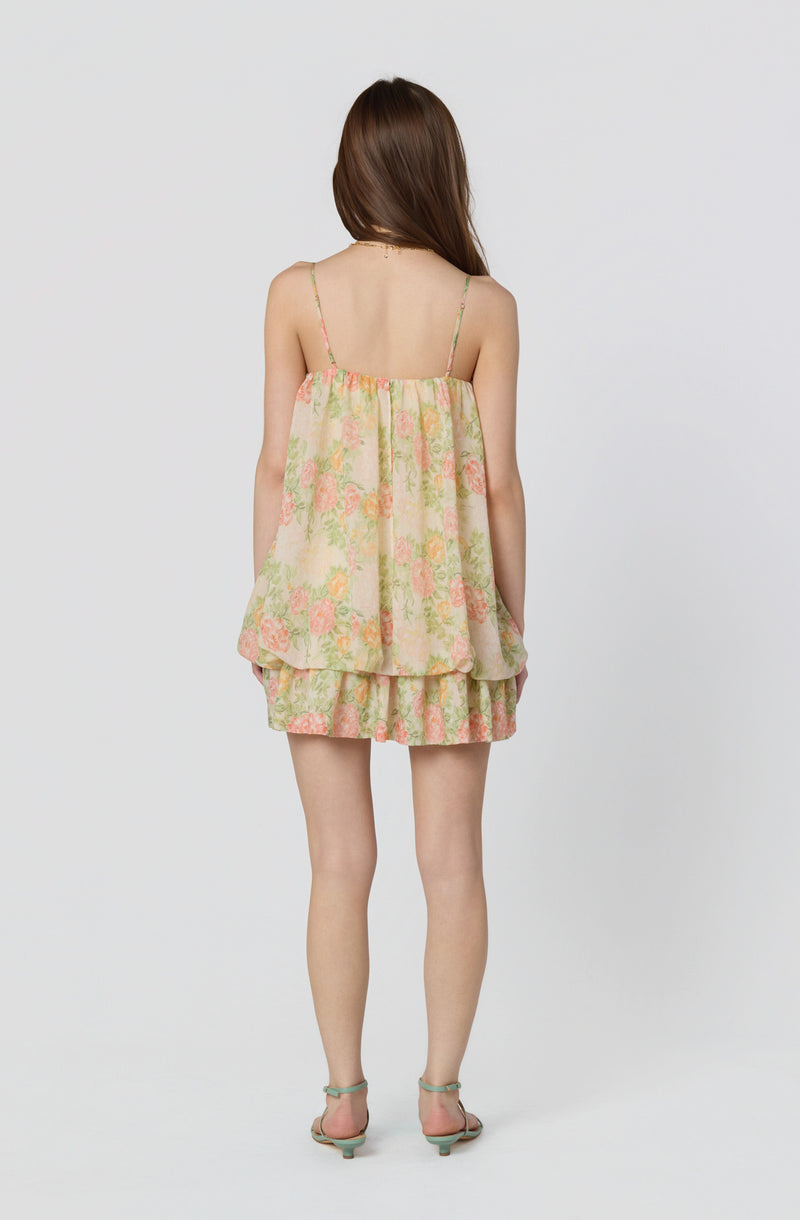 Girl wearing a flowy, floral, sleeveless top with spaghetti straps and matching shorts.