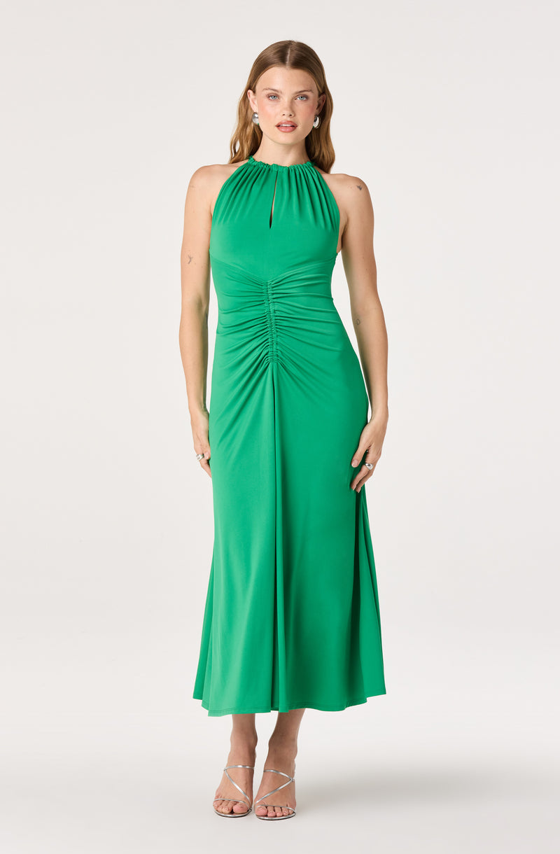 Woman in a green halter maxi dress with ruched details and pleated skirt.