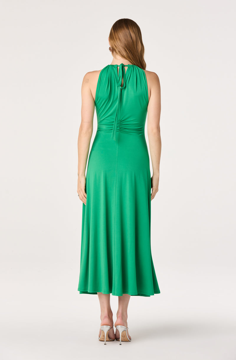 Woman wearing a sleeveless green to darker green ombre dress with a tied neckline.