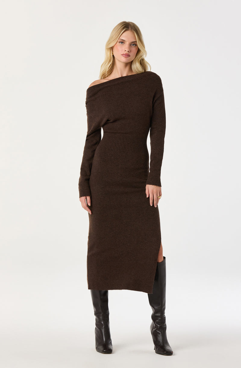 Woman wearing a brown off-shoulder long sweater dress with a side slit and black knee-high boots.