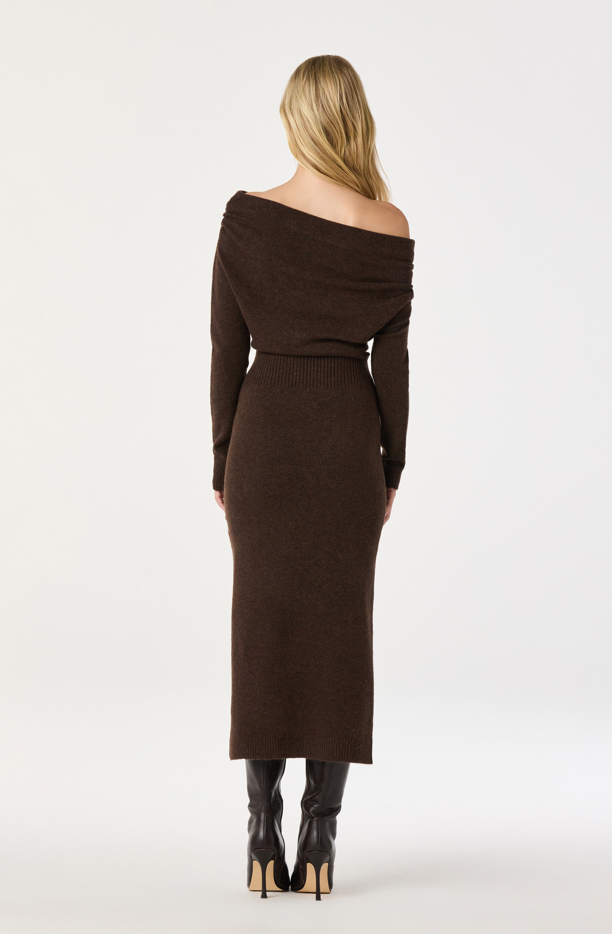 Woman in a brown, off-the-shoulder, long sweater dress with knee-high black boots.