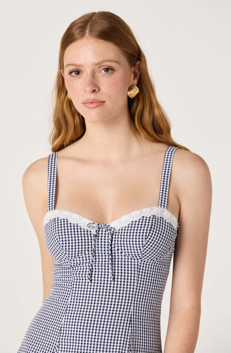 Woman wearing a blue and white checkered sleeveless top with lace trim at the neckline.