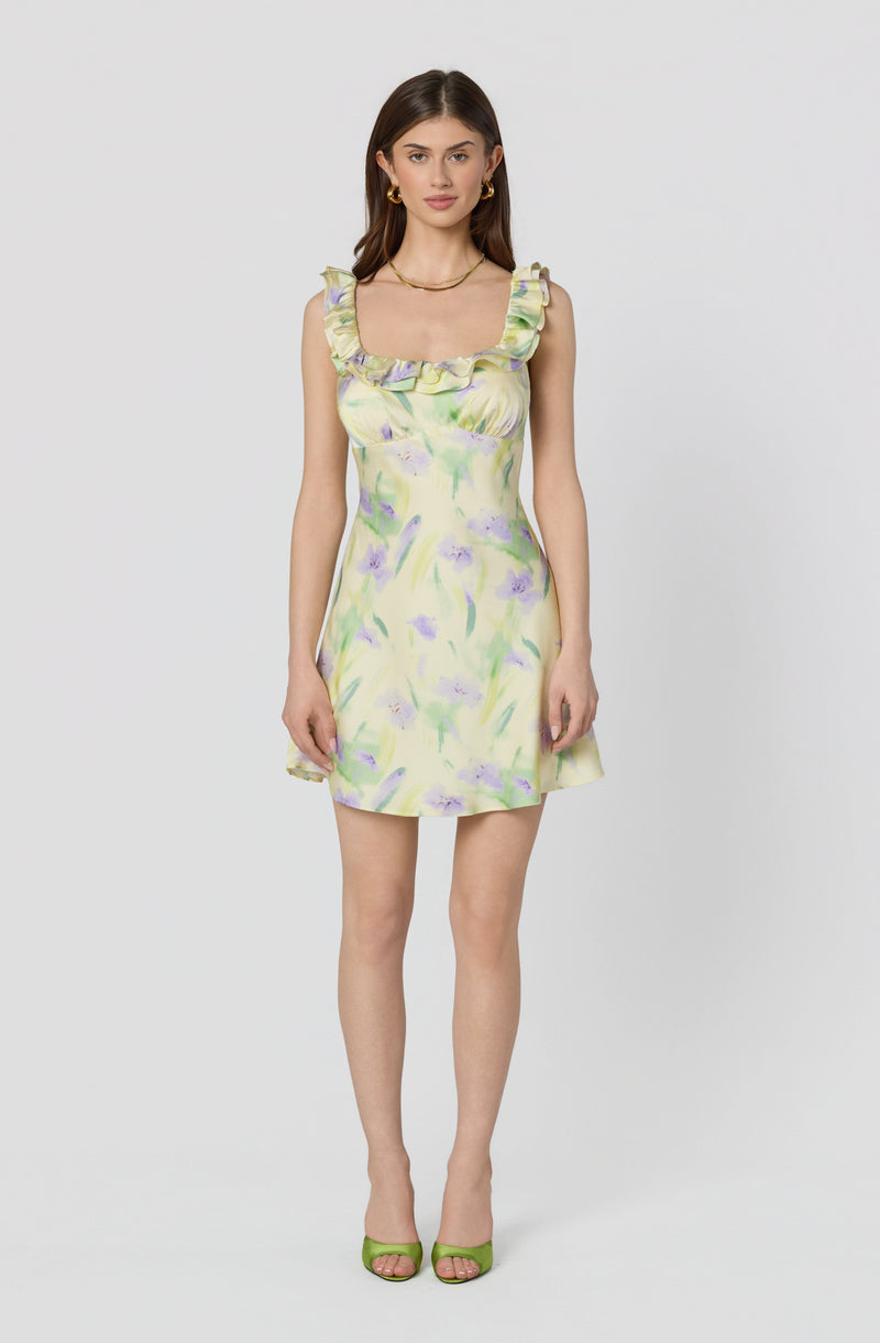 Woman in a pastel floral dress with ruffled straps, paired with green high heels.