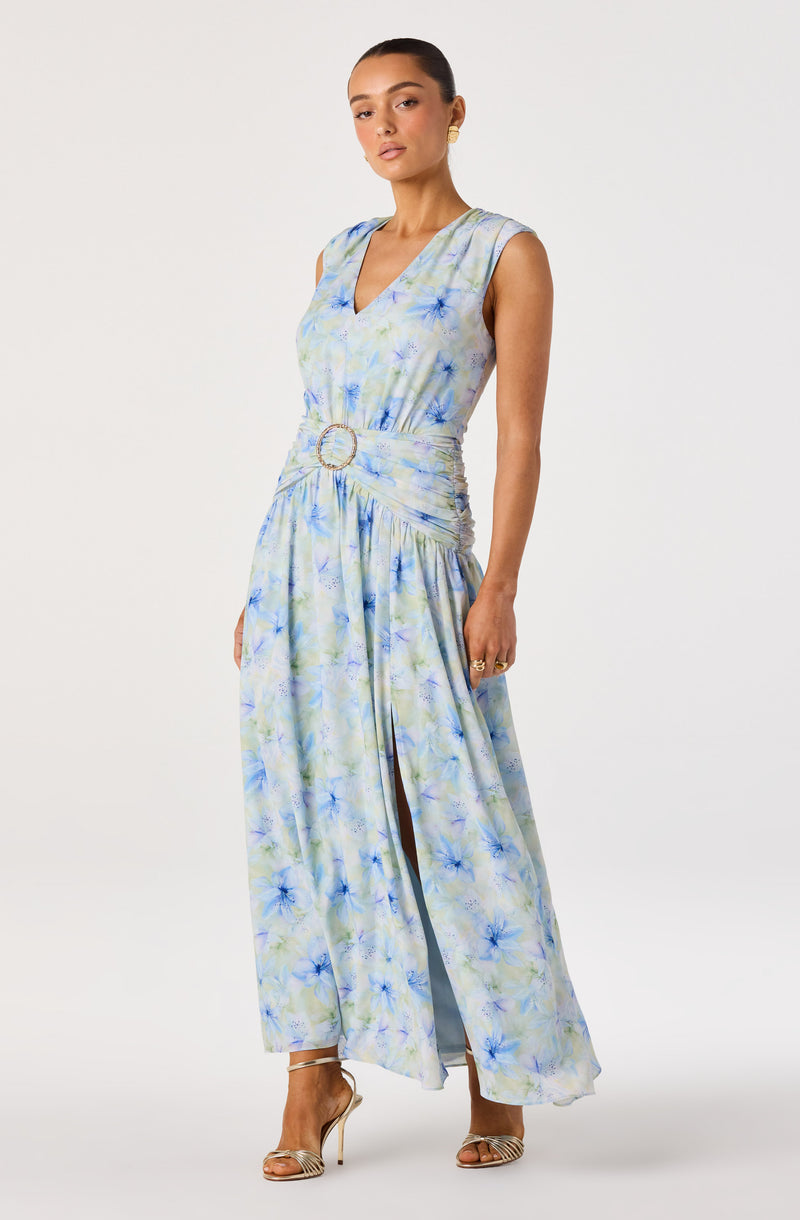 Sleeveless floor-length dress with a pastel floral pattern and a slit, featuring a belt with a circular buckle.
