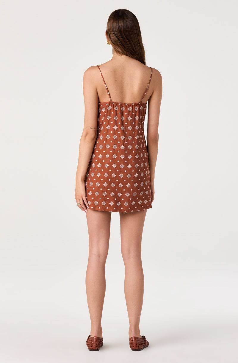 Woman in a brown dress with thin straps and white geometric patterns, paired with matching brown shoes.