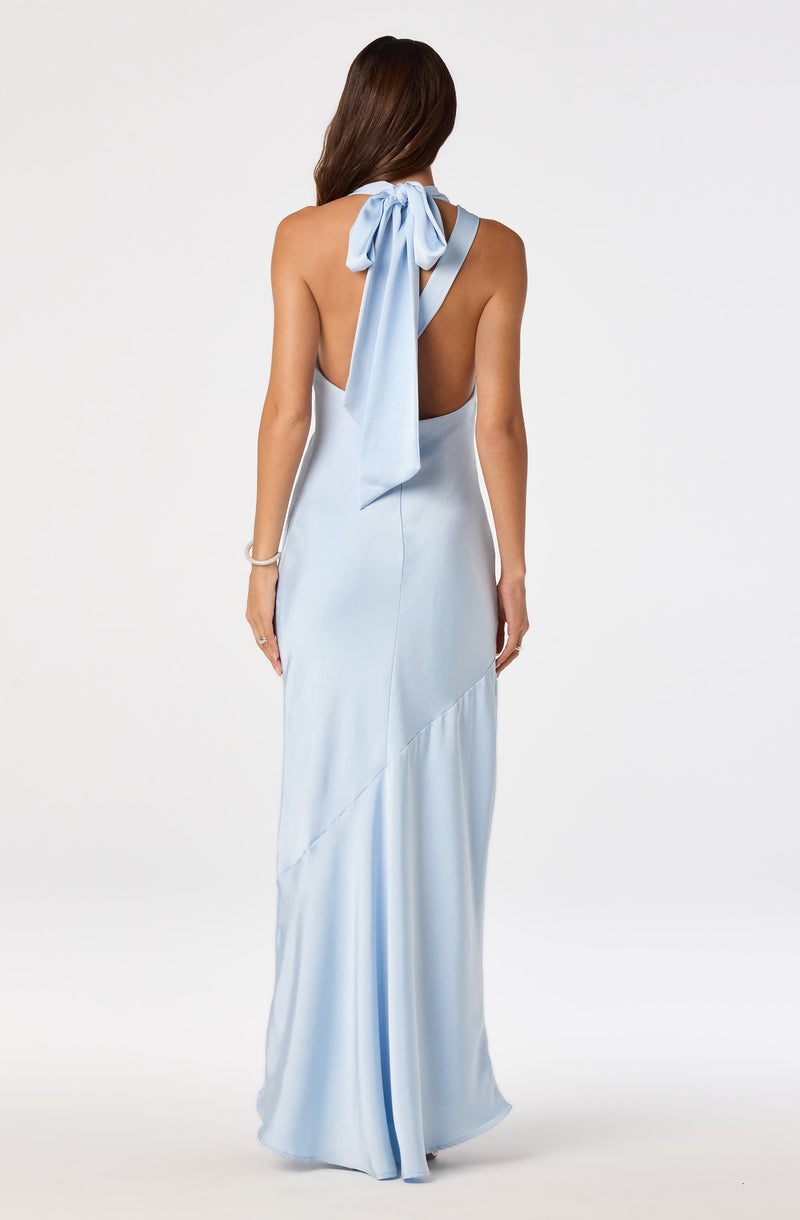 Back view of a woman in a light blue, backless evening gown with a bow detail on the shoulder.