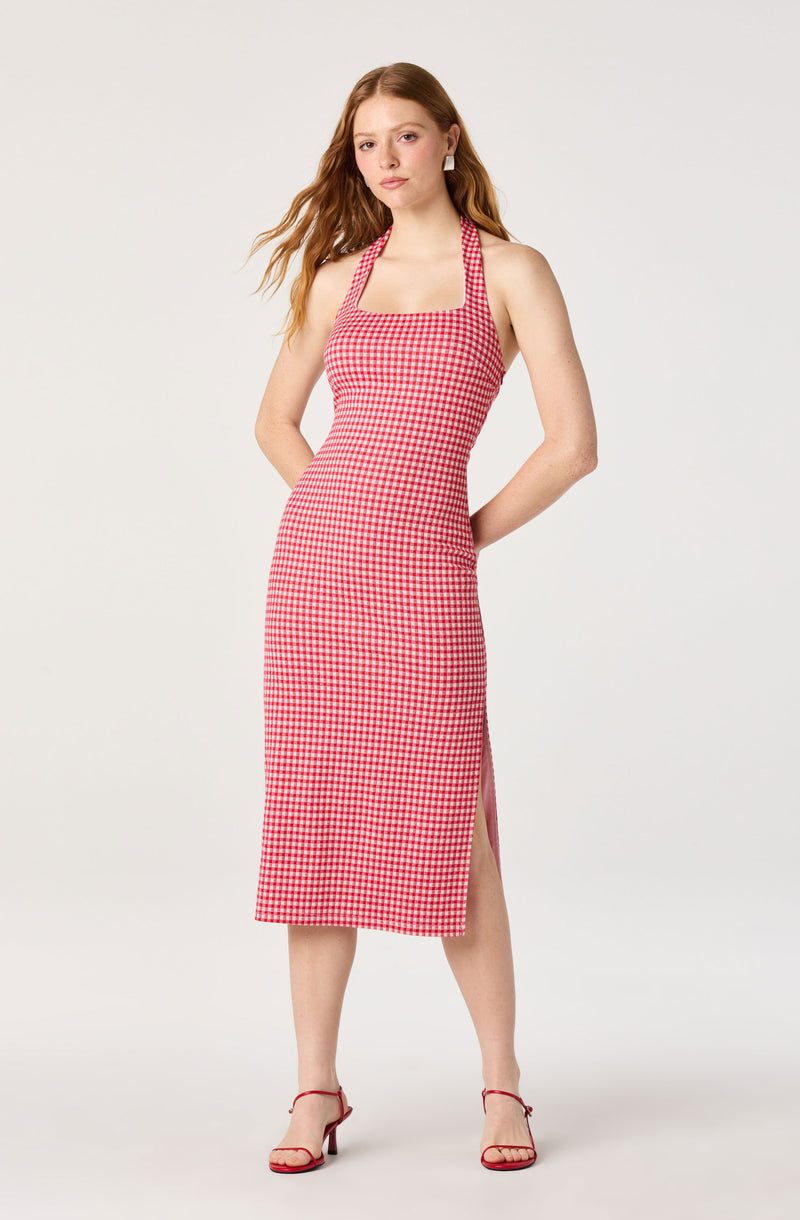 Woman in a red and white checkered halter dress with a side slit, wearing red sandals.