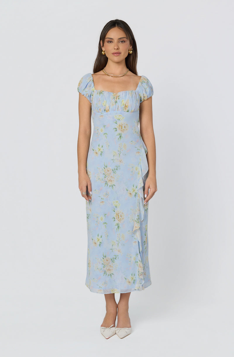 Woman in a light blue floral dress with puff sleeves and a square neckline.