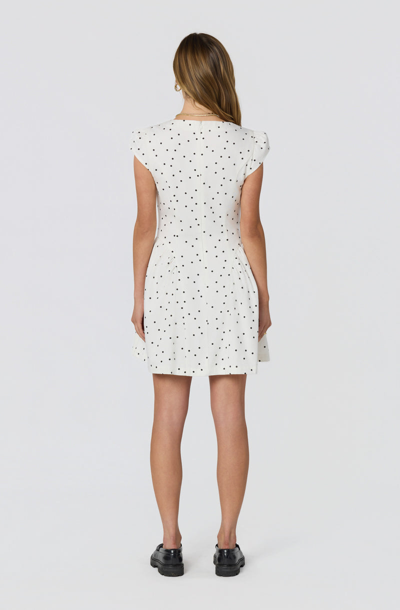 White dress with black polka dots, cap sleeves, and a straight hem.