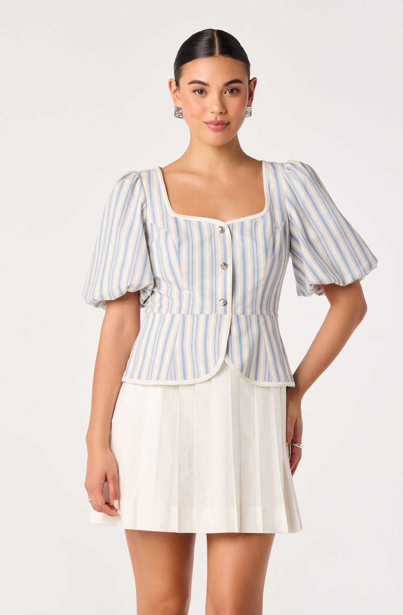 Woman wearing a light blue and white striped peplum top with puffed sleeves and silver buttons.