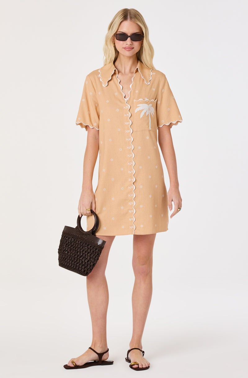 Beige short-sleeve dress with white embroidery, palm tree pocket, ruffled collar, and scalloped edges.