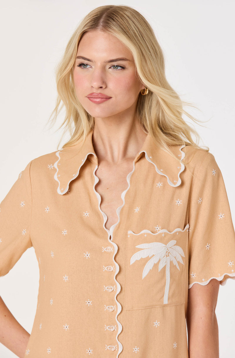 Beige short-sleeve shirt with white floral and palm tree embroidery, scalloped collar and button placket.
