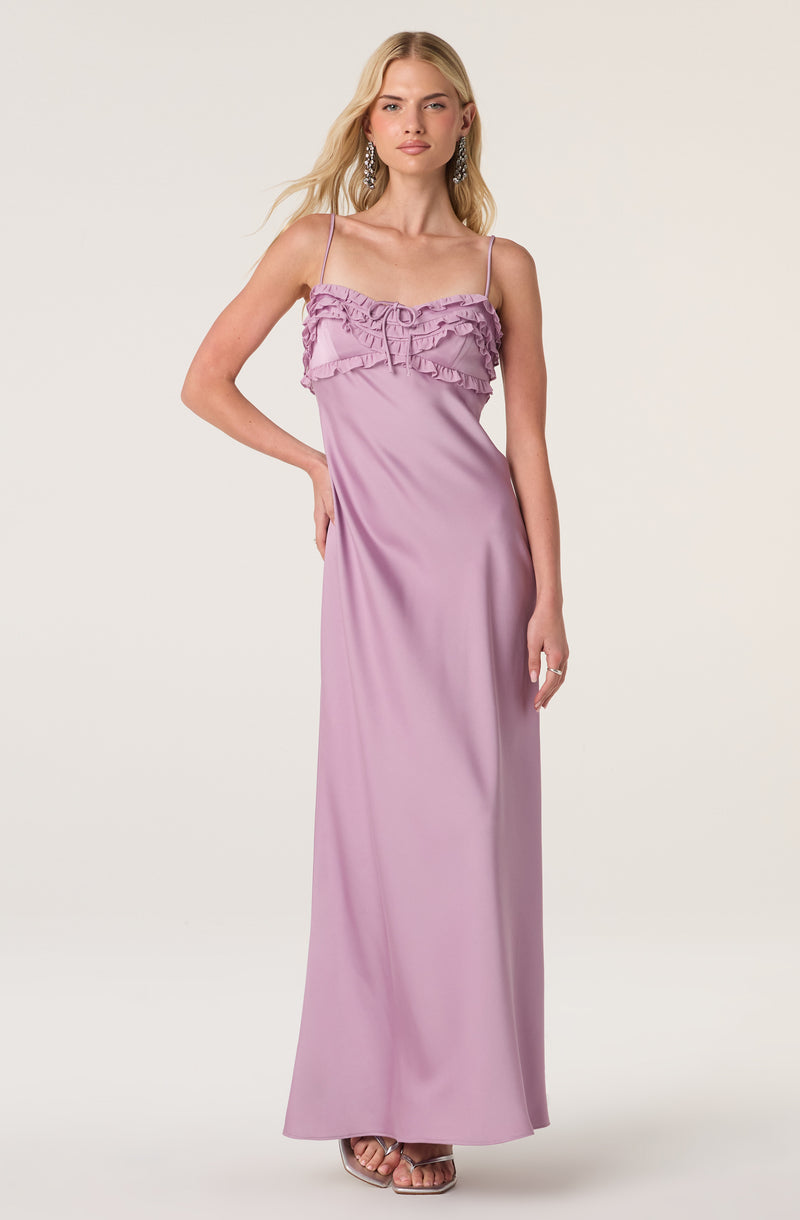 Woman in a full-length lavender satin dress with ruffled top and spaghetti straps.