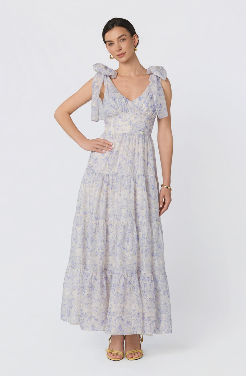 Light-colored, sleeveless maxi dress with shoulder bows and a floral pattern.