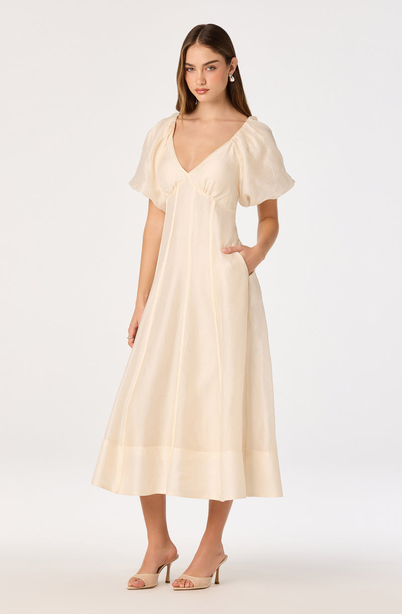 Cream-colored dress with puff sleeves and a V-neck, paired with nude heeled sandals.