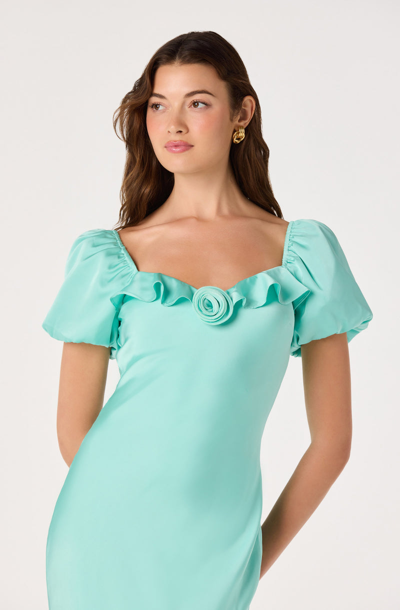 Woman in a turquoise satin dress with ruffled neckline and puffed sleeves.