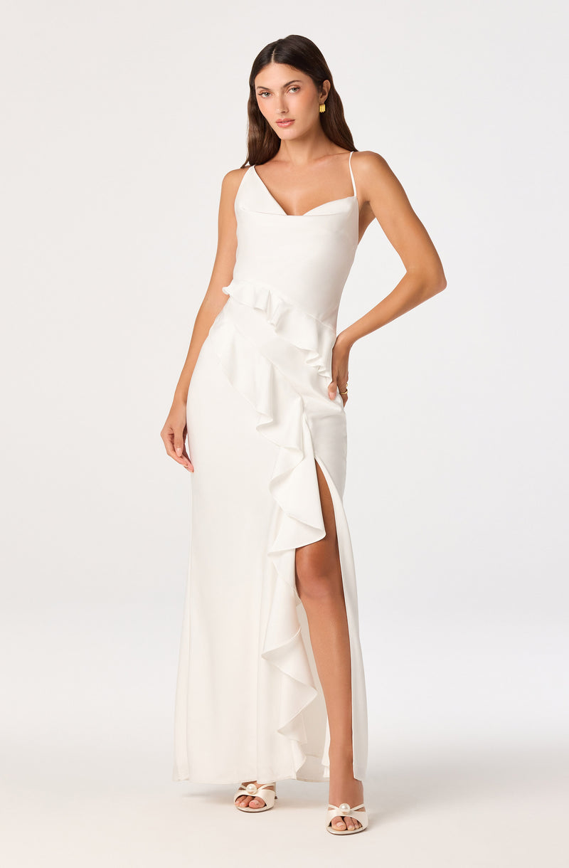 Woman in a white sleeveless dress with ruffle details and a thigh-high slit.