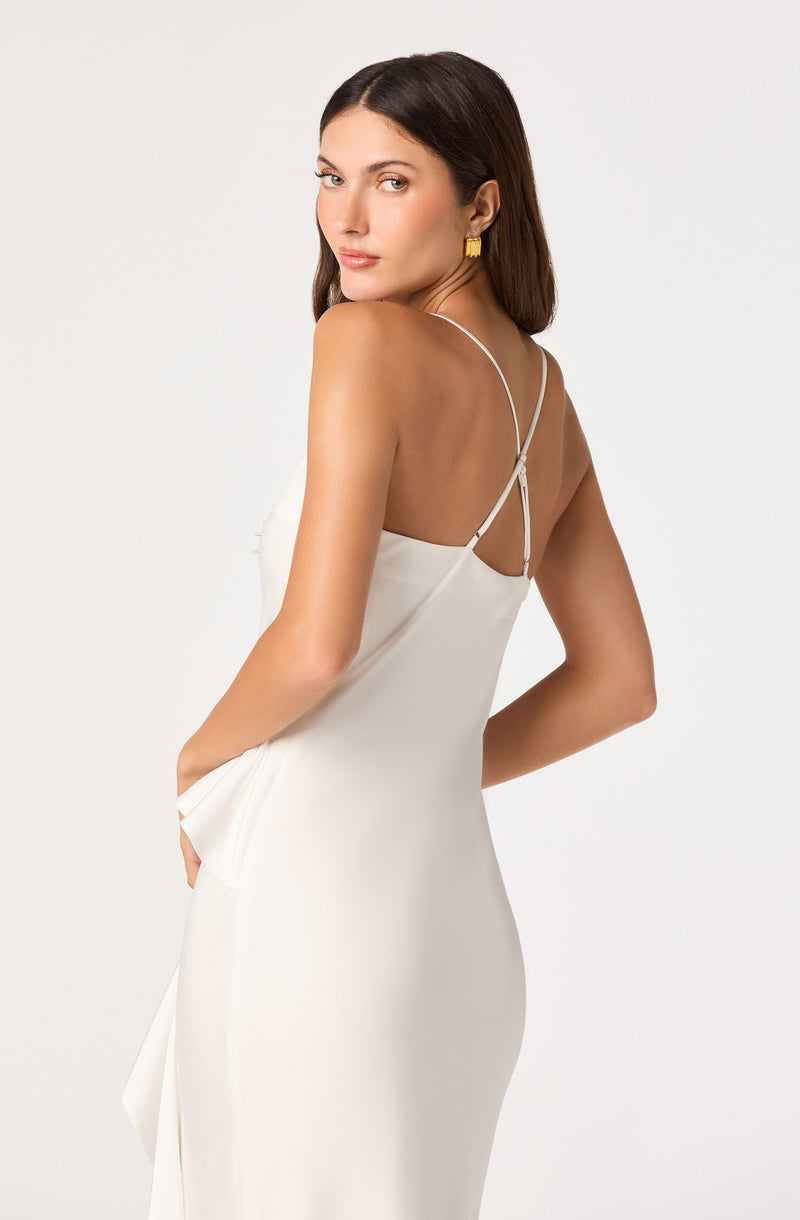 Woman in white slip dress with thin spaghetti straps and gold earrings.