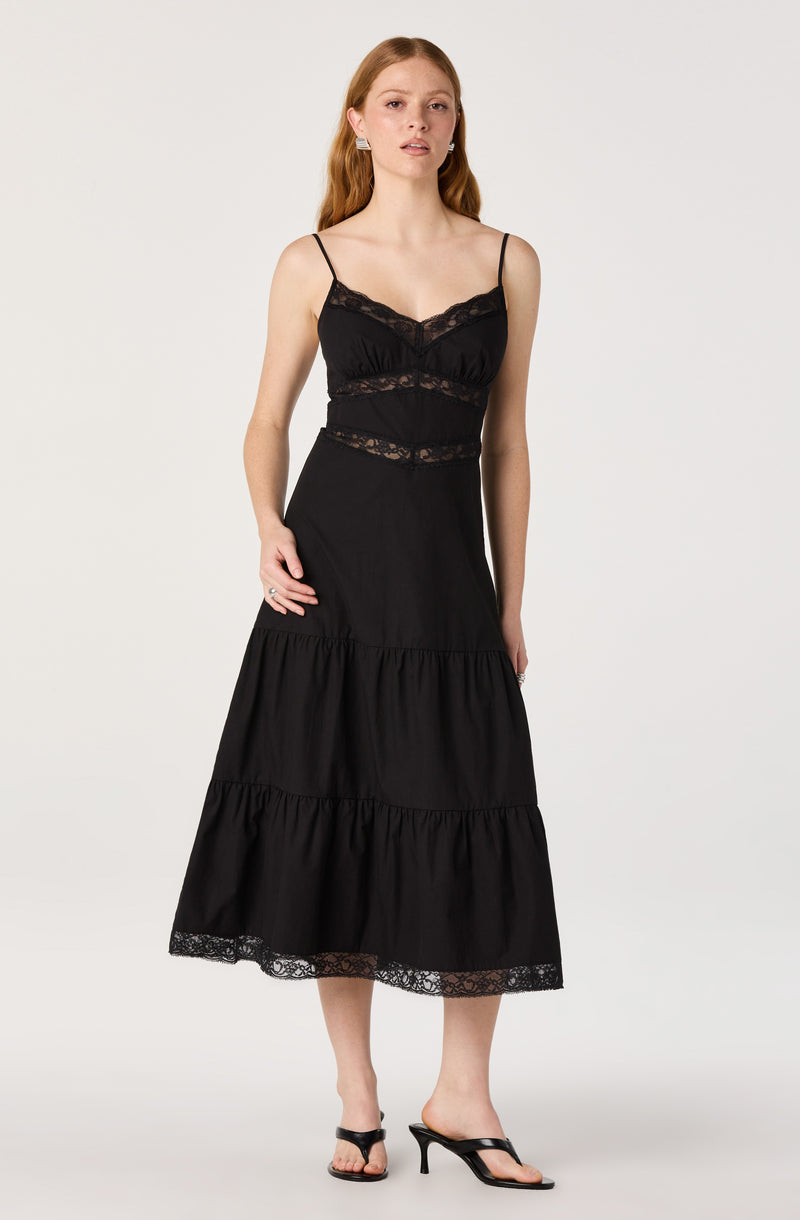 Woman wearing a black lace-trim camisole and a long black tiered skirt with lace details.