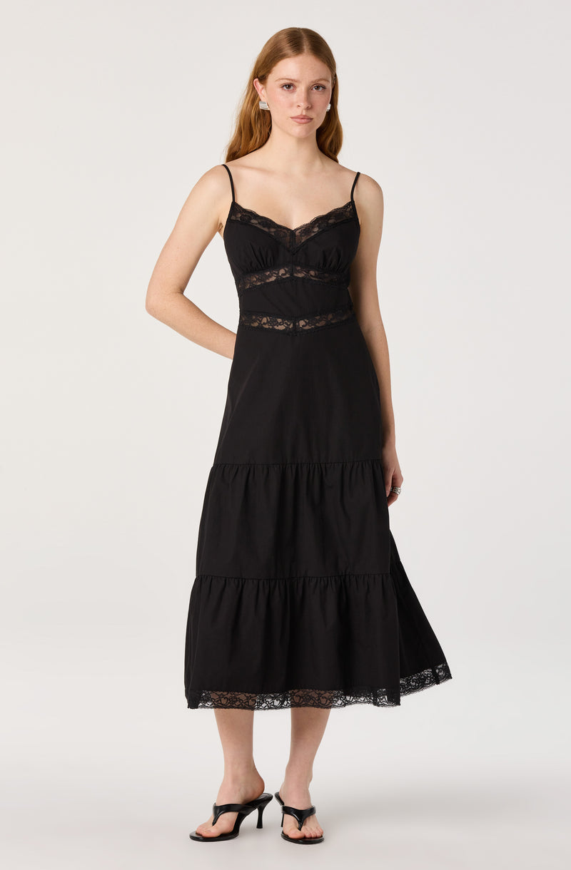 Woman wearing a black maxi dress with lace details and spaghetti straps.