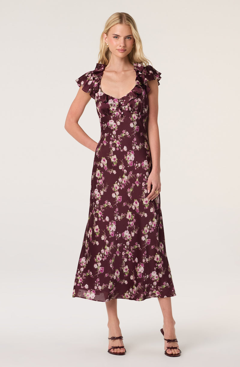 Model wearing a dark purple floral dress with ruffled sleeves and a scoop neckline.