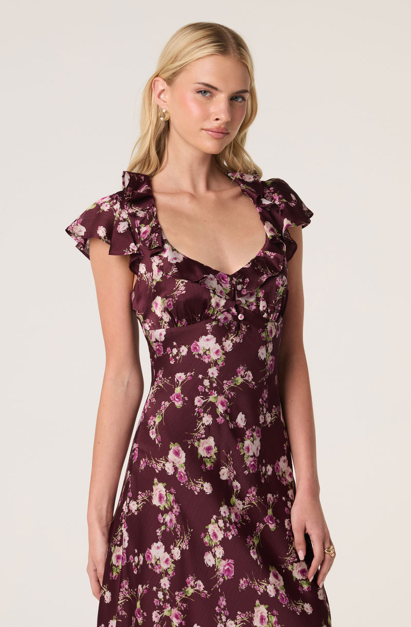 Woman wearing a dark floral dress with ruffled sleeves and a plunging neckline.