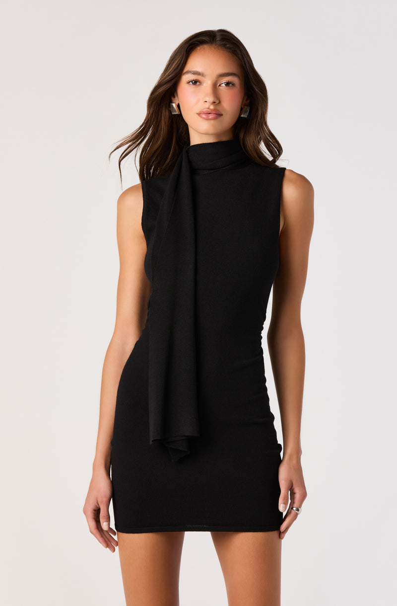 Woman in a sleeveless black dress with a matching black scarf draped around her neck.