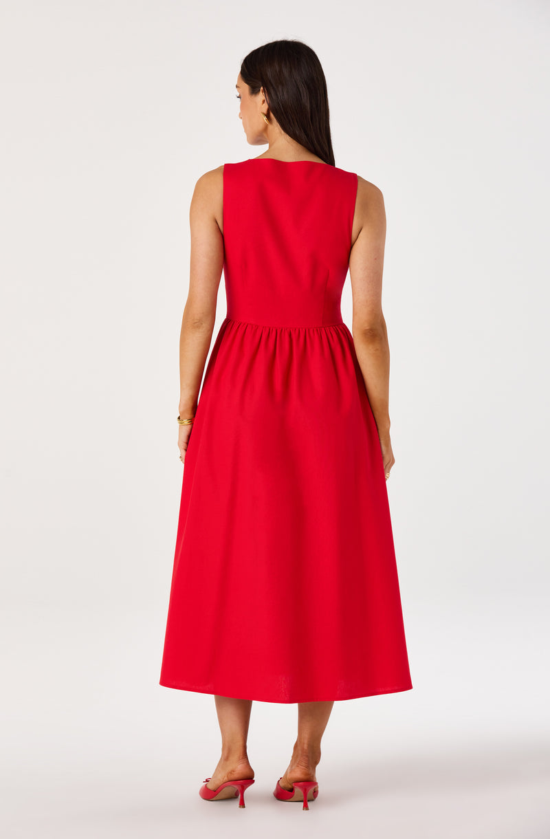 Woman in red sleeveless midi dress with gathered waist, paired with pink heels.