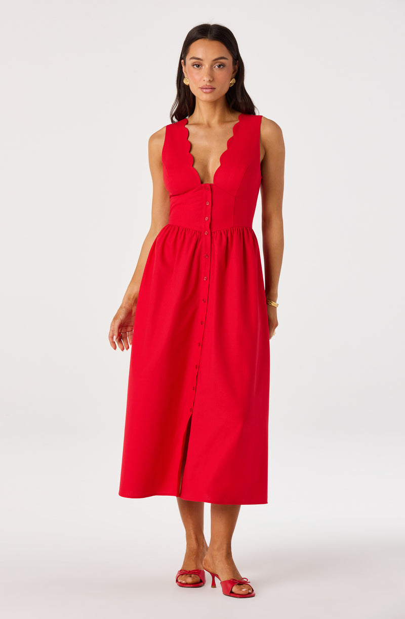 Woman wearing a sleeveless red dress with scalloped neckline and button-down front, paired with red heels.
