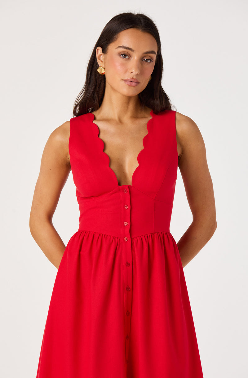 Woman in a red sleeveless dress with scalloped edges and buttons down the front.