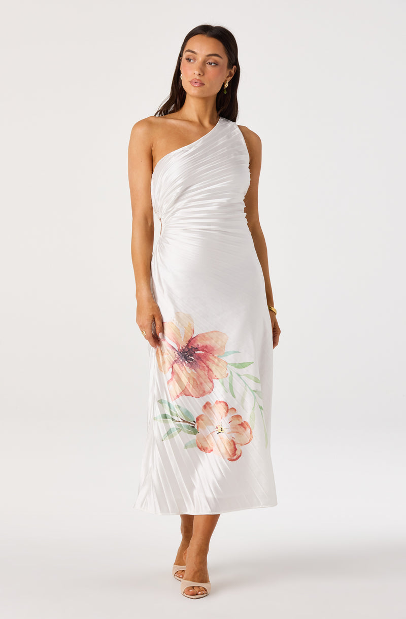Woman wearing a white, one-shoulder dress with floral print at the hem.