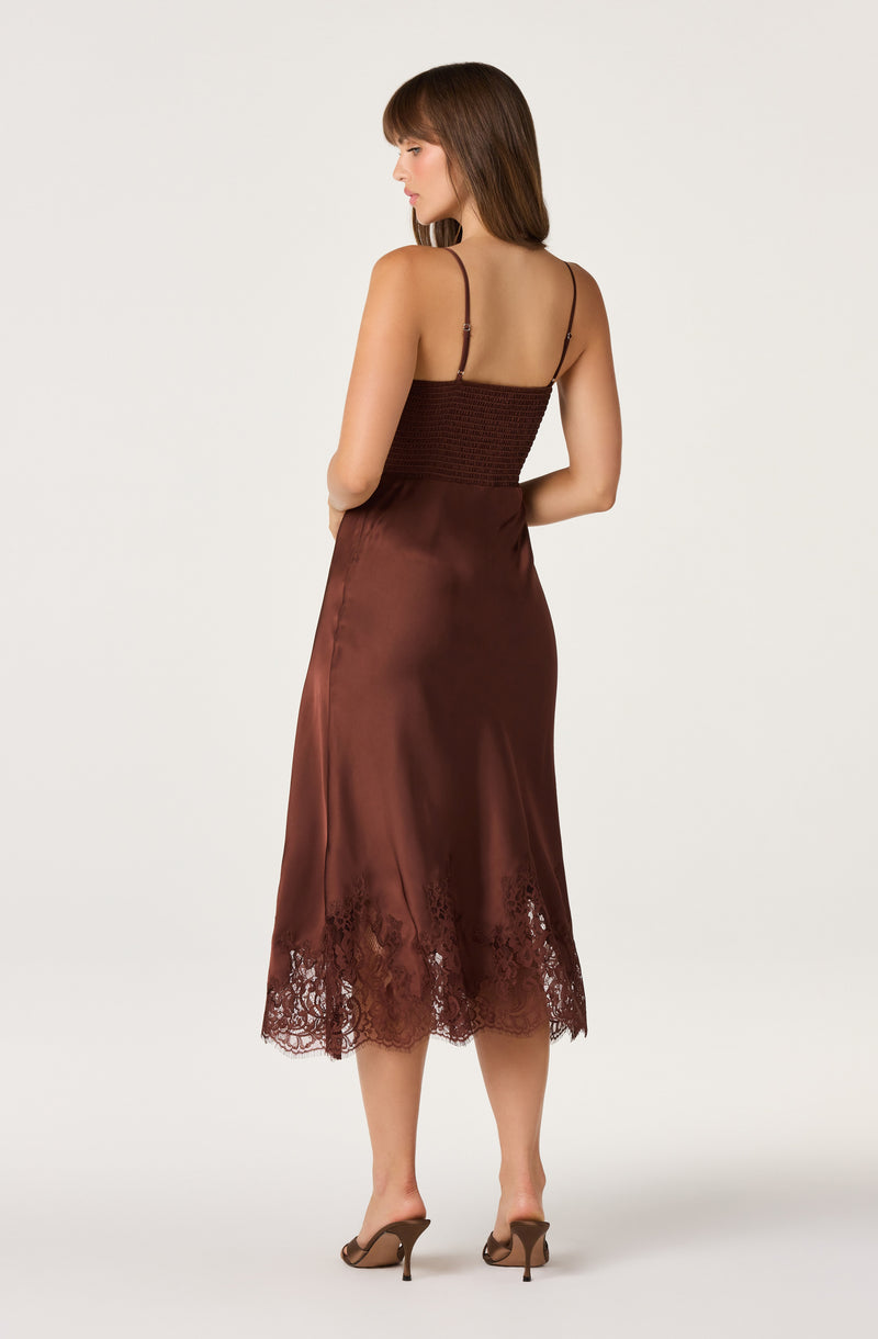 Woman in a brown satin dress with lace hem, spaghetti straps, and a fitted bodice.