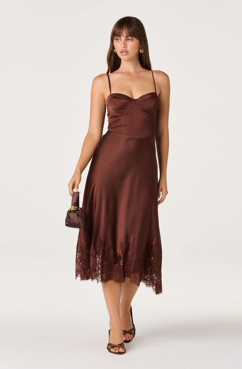 Woman in brown satin slip dress with spaghetti straps and lace trim at the hem.