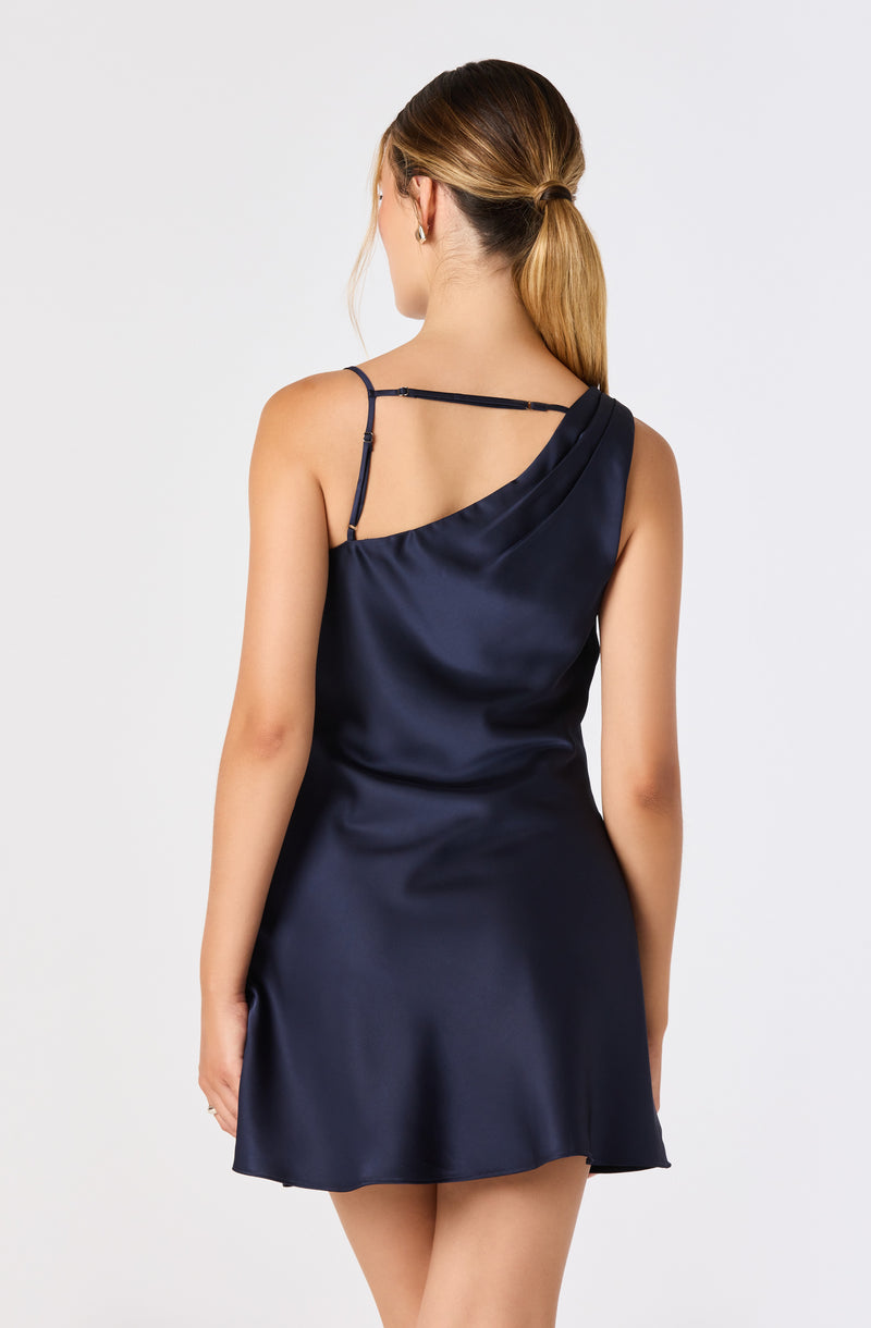 Woman in navy satin slip dress with spaghetti straps and asymmetric neckline.
