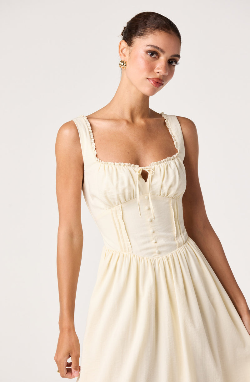 Cream-colored sleeveless dress with ruffled edges and a fitted bodice.