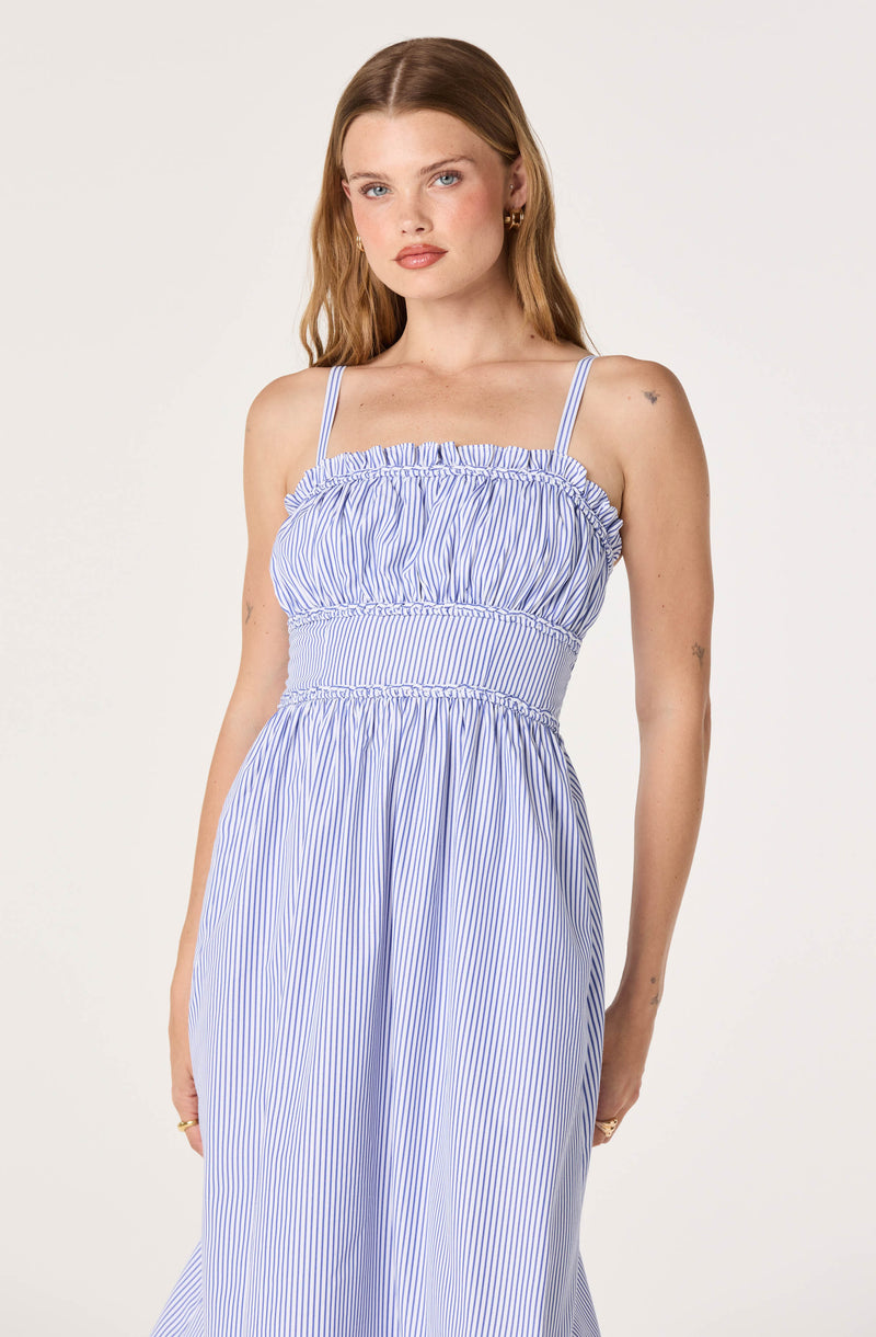 Woman in a blue and white striped sundress with ruffled top and spaghetti straps.