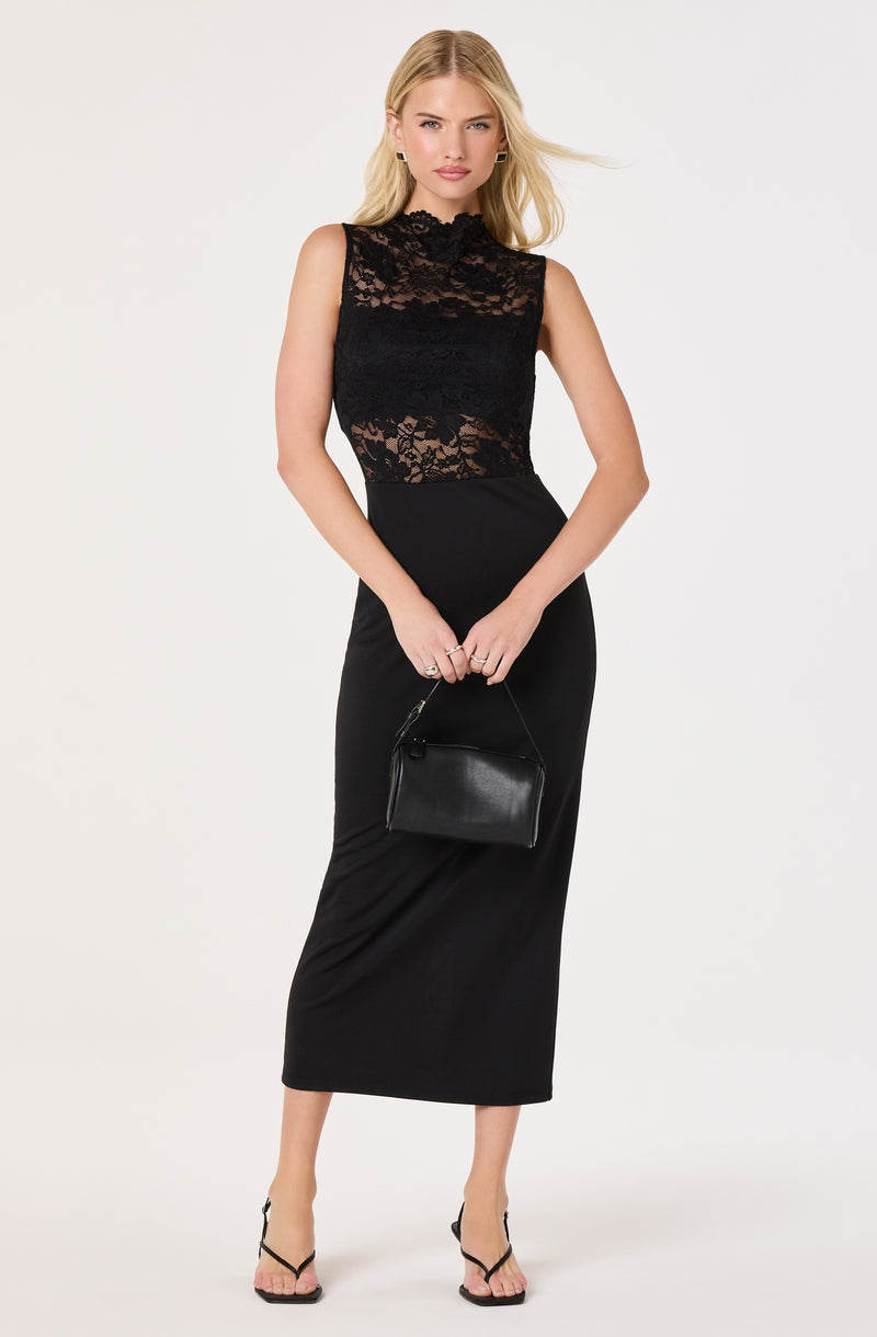 Woman in a sleeveless black lace dress with a high neckline, holding a black handbag.