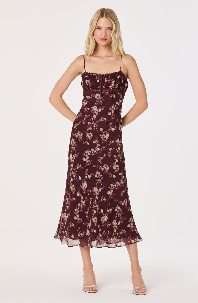 Sleeveless floral dress with spaghetti straps, dark background, pink and white flowers, and ruffled hem.