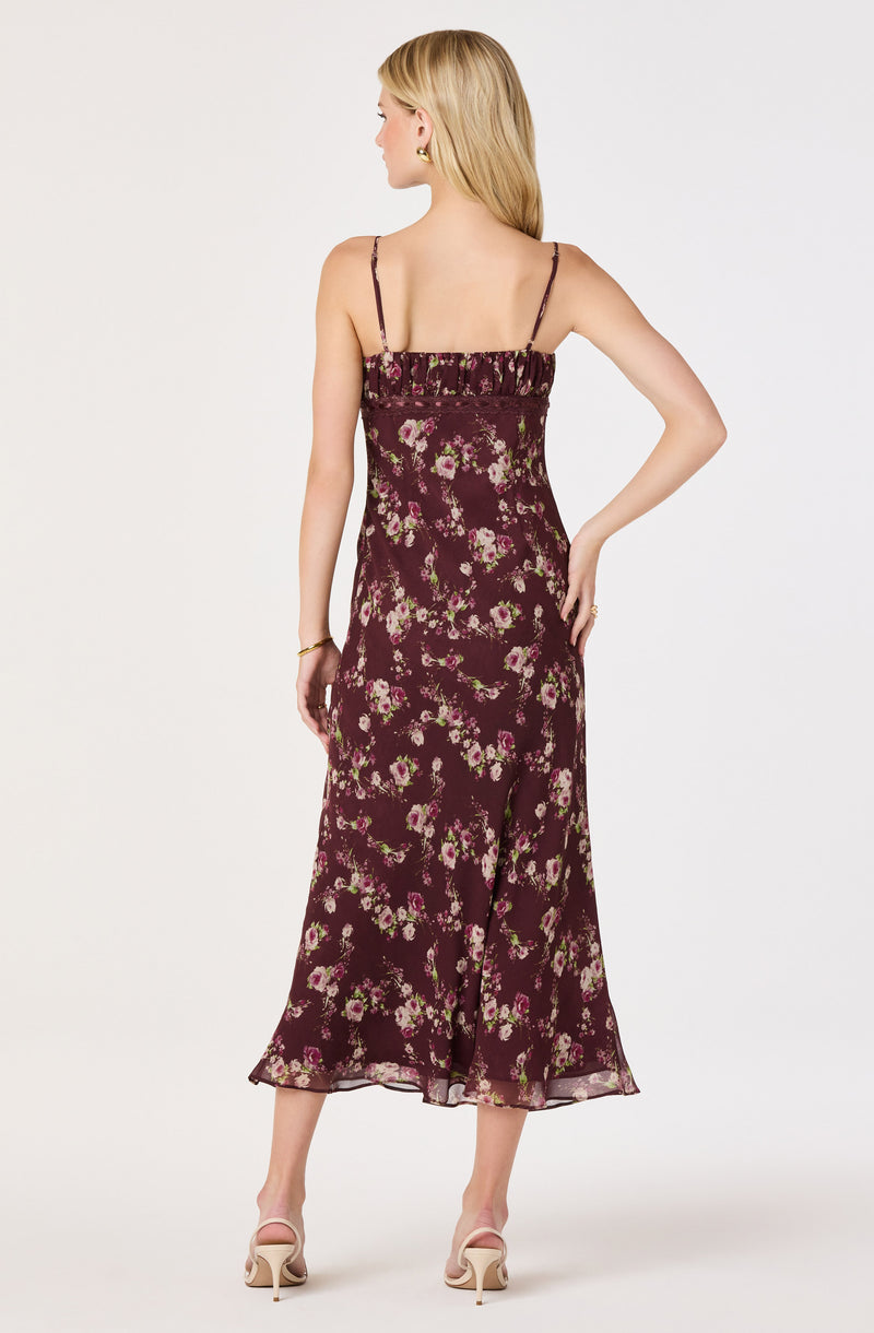 Woman in a burgundy floral slip dress with thin spaghetti straps and ruffled neckline.